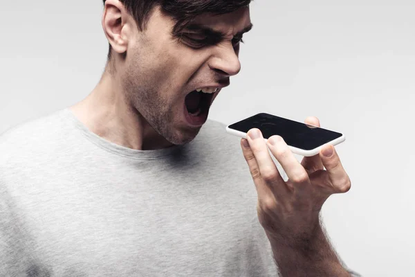 Angry man quarreling on smartphone isolated on grey — Stock Photo