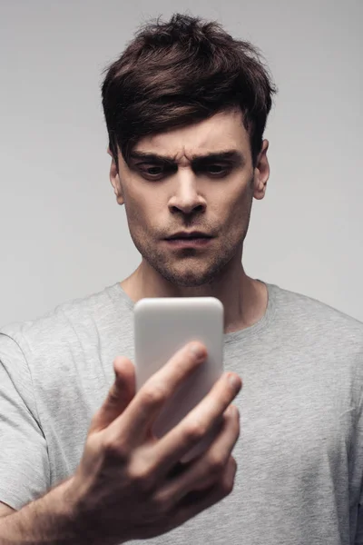 Вдумливий, серйозний чоловік, що має відеочат на смартфоні ізольований на сірому — стокове фото