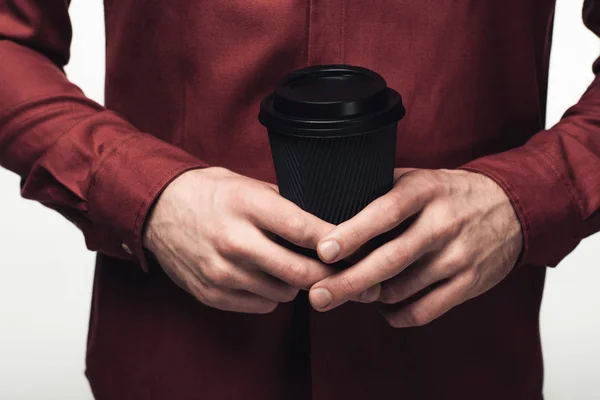 Vista recortada del hombre sosteniendo taza desechable negro aislado en gris - foto de stock