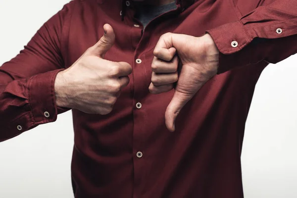 Visión parcial del hombre mostrando pulgar hacia arriba y pulgar hacia abajo aislado en gris, emoción humana y concepto de expresión - foto de stock