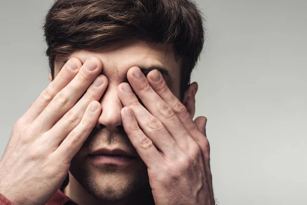 Homem cego cobrindo os olhos com as mãos isoladas em cinza, emoção humana e conceito de expressão — Fotografia de Stock