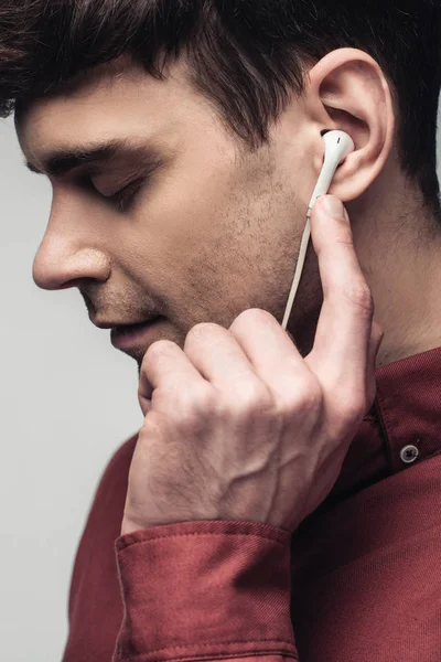 Homem pensativo ouvindo música em fones de ouvido com olhos fechados isolados em cinza — Fotografia de Stock