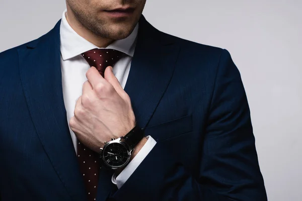 Partial view of businessman touching tie isolated on grey — Stock Photo