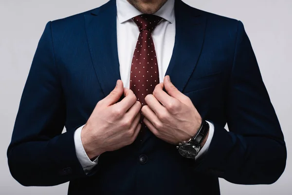 Cropped view of confident businessman touching suit isolated on grey — Stock Photo