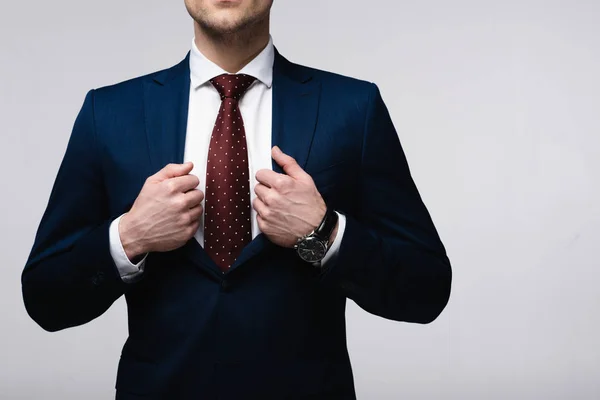 Vista recortada de empresario confiado tocando traje aislado en gris, emoción humana y concepto de expresión - foto de stock