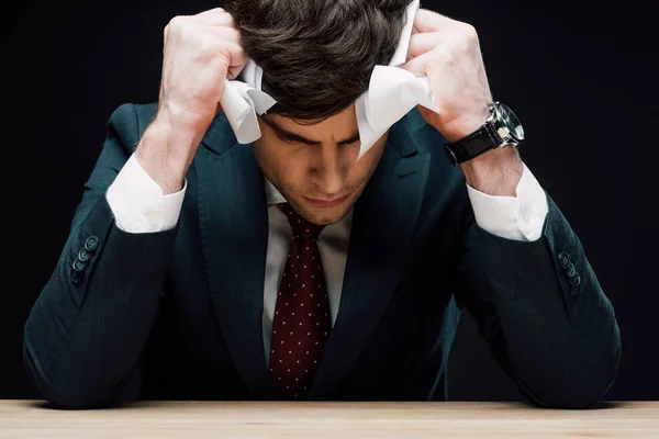 Homme d'affaires déprimé tenant la main avec du papier froissé près de la tête isolé sur noir — Photo de stock