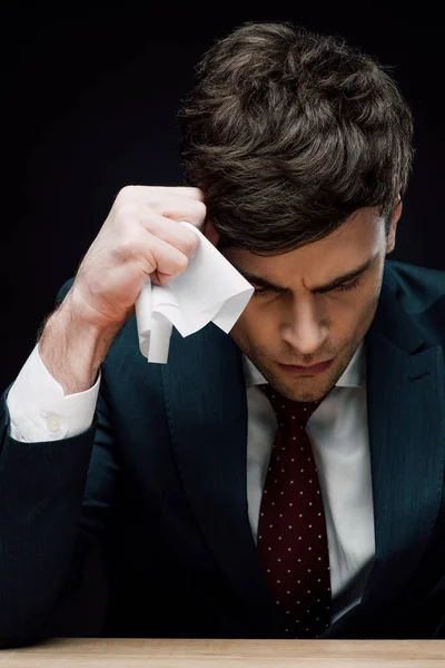 Aufgebrachter Geschäftsmann hält zerknülltes Papier in der Nähe von gesenktem Kopf isoliert auf Schwarz — Stockfoto