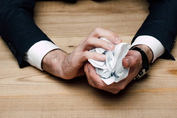 Частичный взгляд бизнесмена, сидящего за столом и крошечной бумагой — стоковое фото