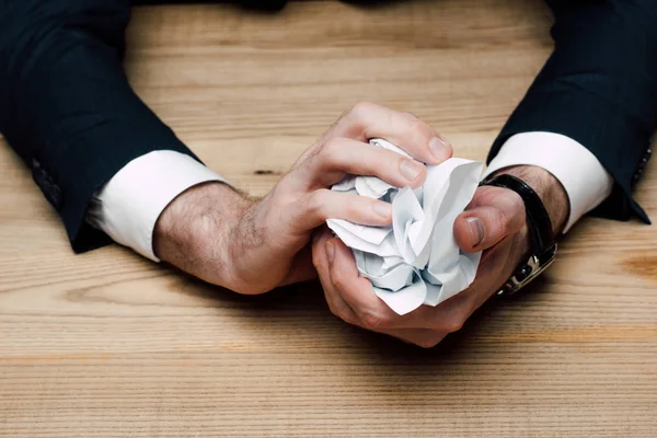 Teilansicht eines Geschäftsmannes, der am Tisch sitzt und Papier zerknüllt — Stockfoto