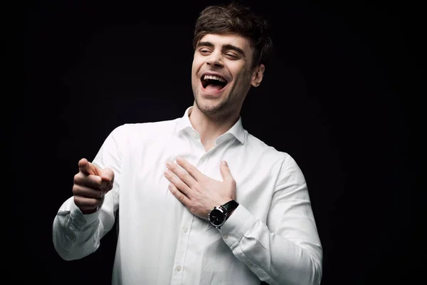 Empresário alegre rindo e apontando com o dedo isolado em preto, emoção humana e conceito de expressão — Fotografia de Stock