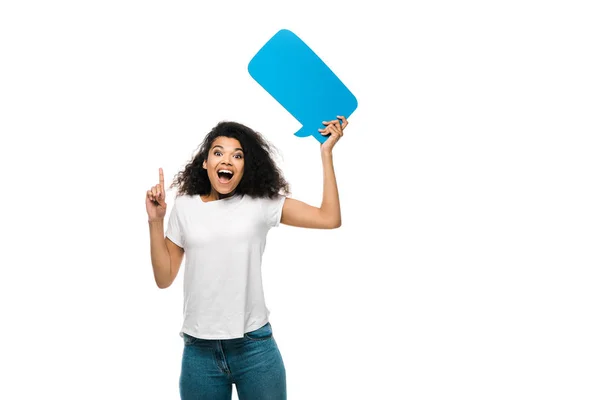 Felice ragazza afro-americana tenendo la bolla discorso blu mentre punta con il dito isolato su bianco — Foto stock