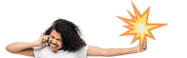 Plano panorámico de la chica afro-americana emocional con los ojos cerrados cubriendo la oreja y sosteniendo la burbuja cómica aislada en blanco - foto de stock