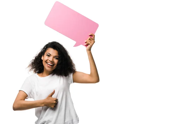 Cheerful african american girl holding pink speech bubble and showing thumb up isolated on white — Stock Photo
