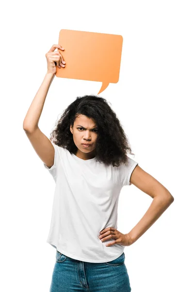 Upset african american girl holding orange speech bubble and standing with hand on hip isolated on white — Stock Photo