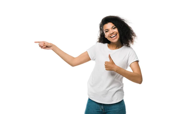 Alegre afroamericana chica mostrando el pulgar hacia arriba y señalando con el dedo aislado en blanco - foto de stock