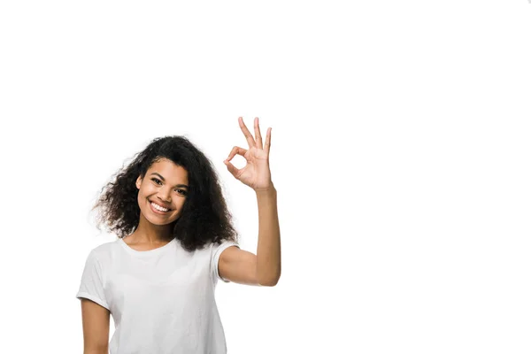 Glücklich und lockig afrikanisch amerikanische Mädchen zeigt ok Zeichen isoliert auf weiß — Stockfoto
