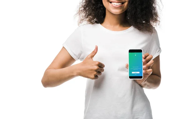 KYIV, UKRAINE - MAIO 29, 2019: visão recortada da menina americana feliz segurando smartphone com aplicativo twitter na tela e mostrando o polegar isolado no branco — Fotografia de Stock