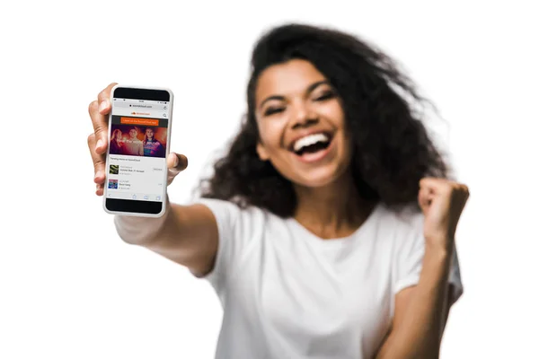 KYIV, UKRAINE - MAY 29, 2019: selective focus of happy american girl holding smartphone with soundcloud app on screen and gesturing isolated on white — Stock Photo