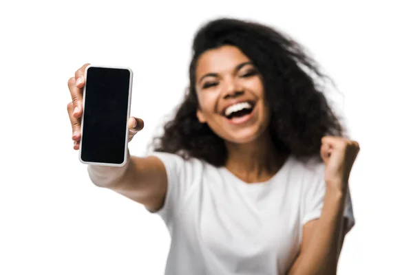Enfoque selectivo de la niña afroamericana feliz sosteniendo teléfono inteligente con pantalla en blanco y celebrando aislado en blanco - foto de stock