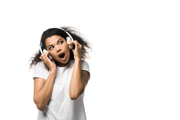 Здивована афроамериканець дівчина в навушниках прослуховування музики, ізольованих на білому — стокове фото