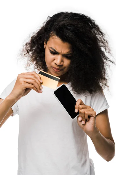 Focado Africano americano mulher segurando cartão de crédito perto de smartphone com tela em branco isolado no branco — Fotografia de Stock