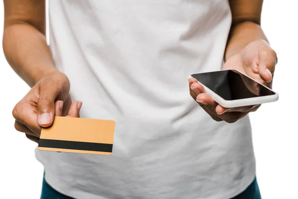 Ausgeschnittene Ansicht einer afrikanisch-amerikanischen Frau mit Kreditkarte in der Nähe von Smartphone mit leerem Bildschirm isoliert auf weiß — Stockfoto