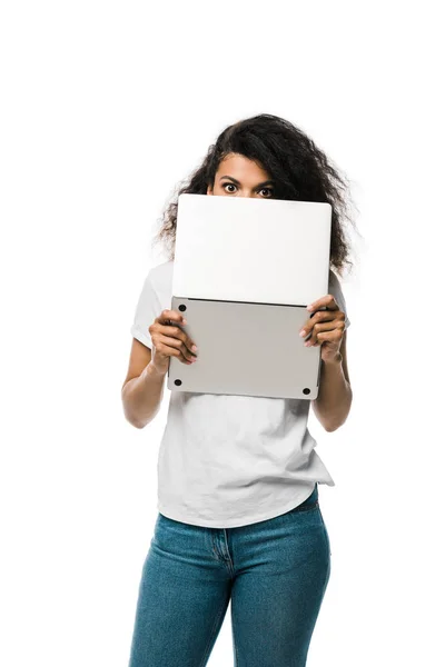 Curly african american girl covering face with laptop isolated on white — Stock Photo