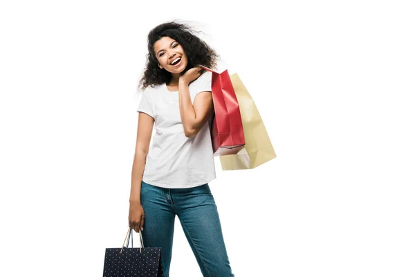 Alegre menina afro-americana segurando sacos de compras enquanto estava isolado no branco — Fotografia de Stock