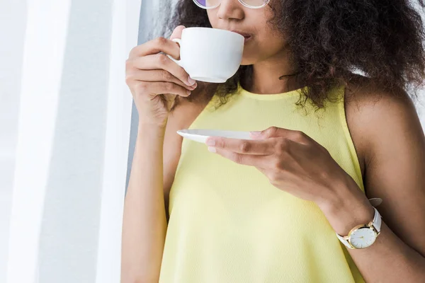 Cropped view of african american woman drinking coffee from cup — Stock Photo