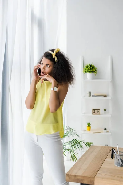 Surprised curly african american woman talking on smartphone — Stock Photo