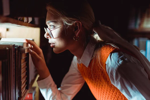 Side view of beautiful woman in glasses looking away in library — Stock Photo