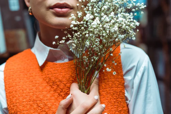 Vista recortada de la mujer joven adulta sosteniendo flores blancas - foto de stock