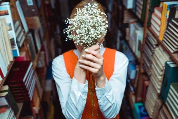 Messa a fuoco selettiva della donna che tiene fiori bianchi in biblioteca — Foto stock