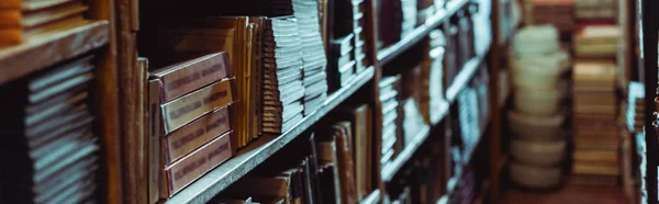 Panoramic shot of retro books on wooden shelves in library — Stock Photo