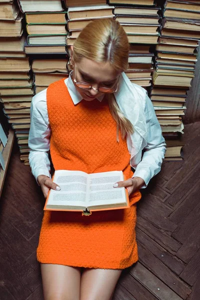 Aus der Vogelperspektive: Schöne Frau sitzt auf dem Boden und liest Buch in der Bibliothek — Stockfoto