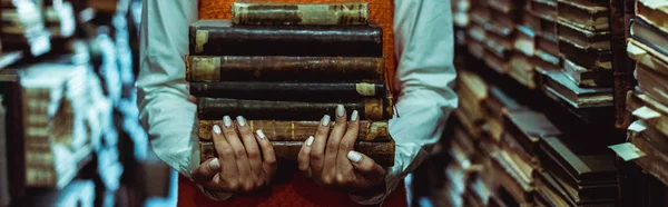 Panoramic shot of woman holding retro books in library — Stock Photo