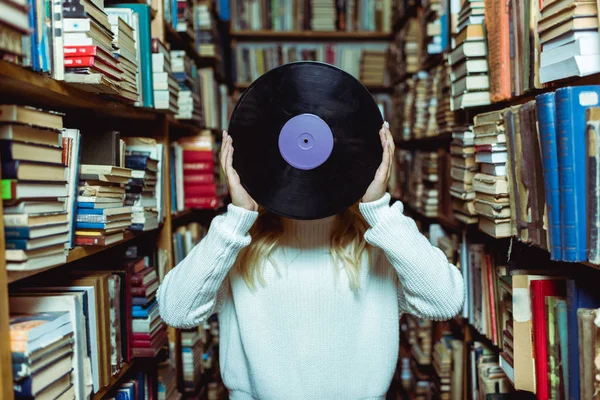 Vue recadrée d'une jeune femme adulte tenant du vinyle dans une bibliothèque — Photo de stock