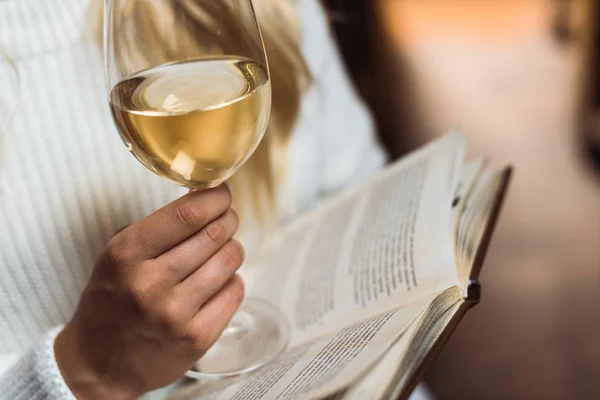 Vue recadrée de jeune femme adulte tenant verre à vin et livre — Photo de stock