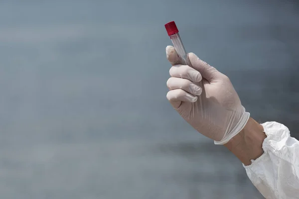 Partial view of water inspector in latex glove holding test tube — Stock Photo