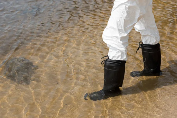 Vista recortada del inspector de agua en traje de protección y botas de pie en el río - foto de stock