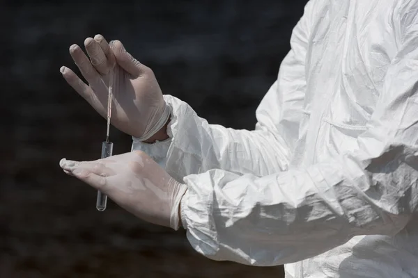 Vista parcial del inspector de agua en guantes de látex con tubo de ensayo tomando muestra de agua - foto de stock