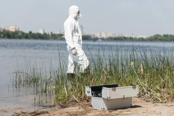 Foyer sélectif de l'inspecteur de l'eau en costume de protection et trousse d'inspection au premier plan — Photo de stock