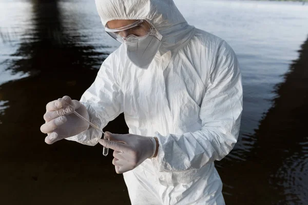 Teilansicht des Wasserinspektors in Atemschutzmaske und Schutzbrille bei der Entnahme von Wasserproben — Stockfoto