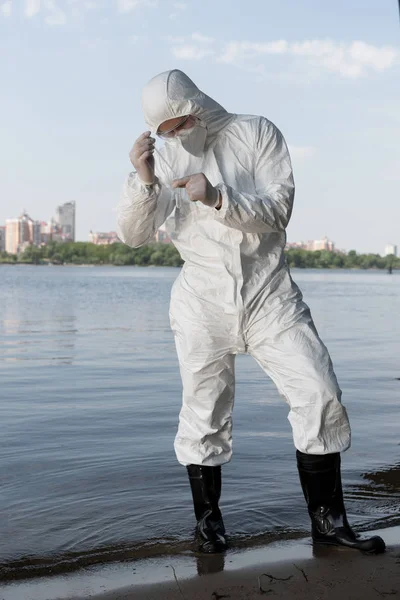 Full length view of water inspector in protective costume and latex gloves taking water sample — Stock Photo