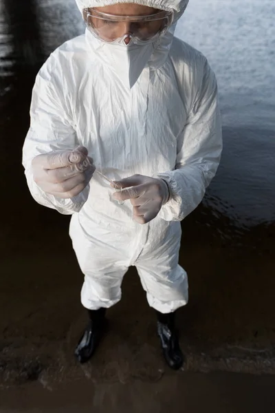 Високий кут зору інспектора води в захисному костюмі, що приймає зразок води на річці — Stock Photo