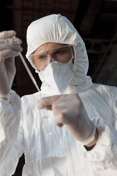 Inspector de agua en traje de protección, respirador y gafas tomando la muestra de agua - foto de stock