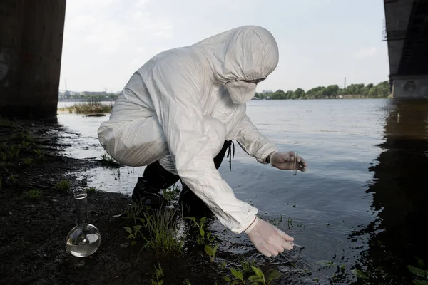 Ispettore dell'acqua in costume protettivo e respiratore che preleva campioni d'acqua al fiume — Foto stock