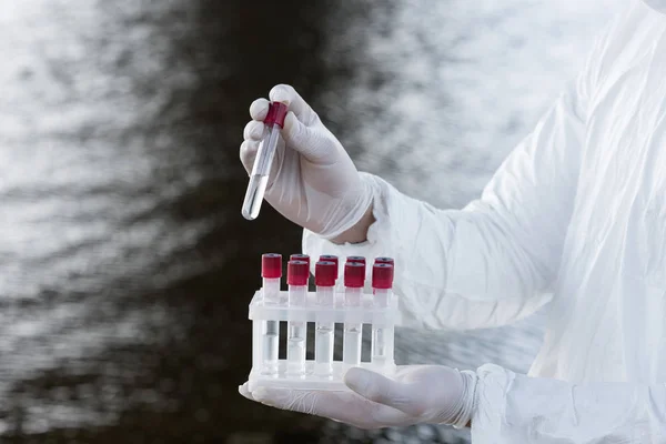 Teilansicht des Wasserinspektors im Schutzanzug mit Reagenzgläsern — Stockfoto