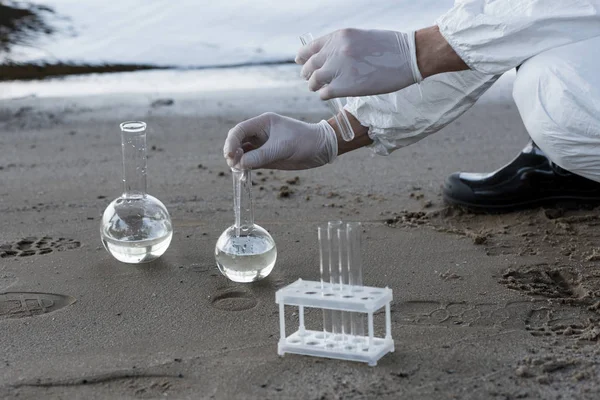 Partial view of water inspector in latex gloves taking water samples at river — Stock Photo