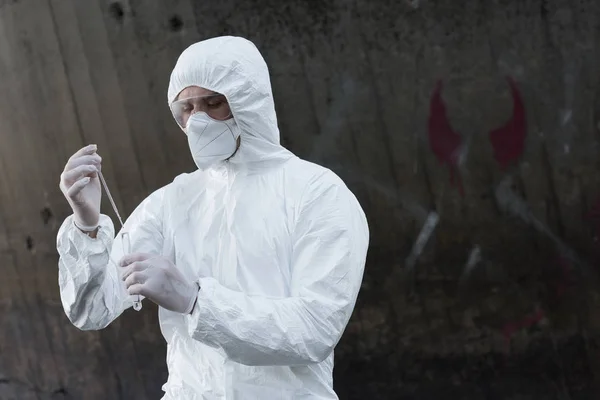 Water inspector in protective costume and respirator taking water sample — Stock Photo